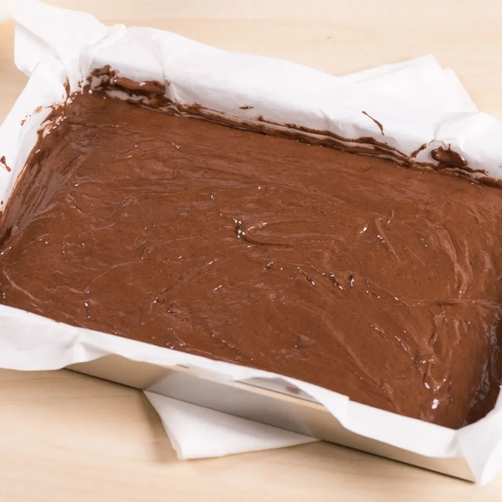Batter for lactation brownies in a baking pan lined with parchment paper.