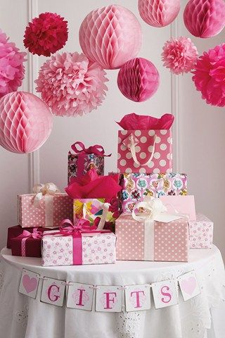 Pom pom balls hanging above gift table at baby shower