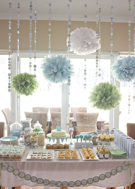 Food table at a baby shower with pom poms hanging over it