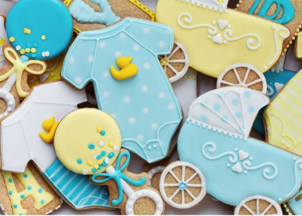Custom baby shower cookies in blue and yellow with carriage, rattle, and onesie design.