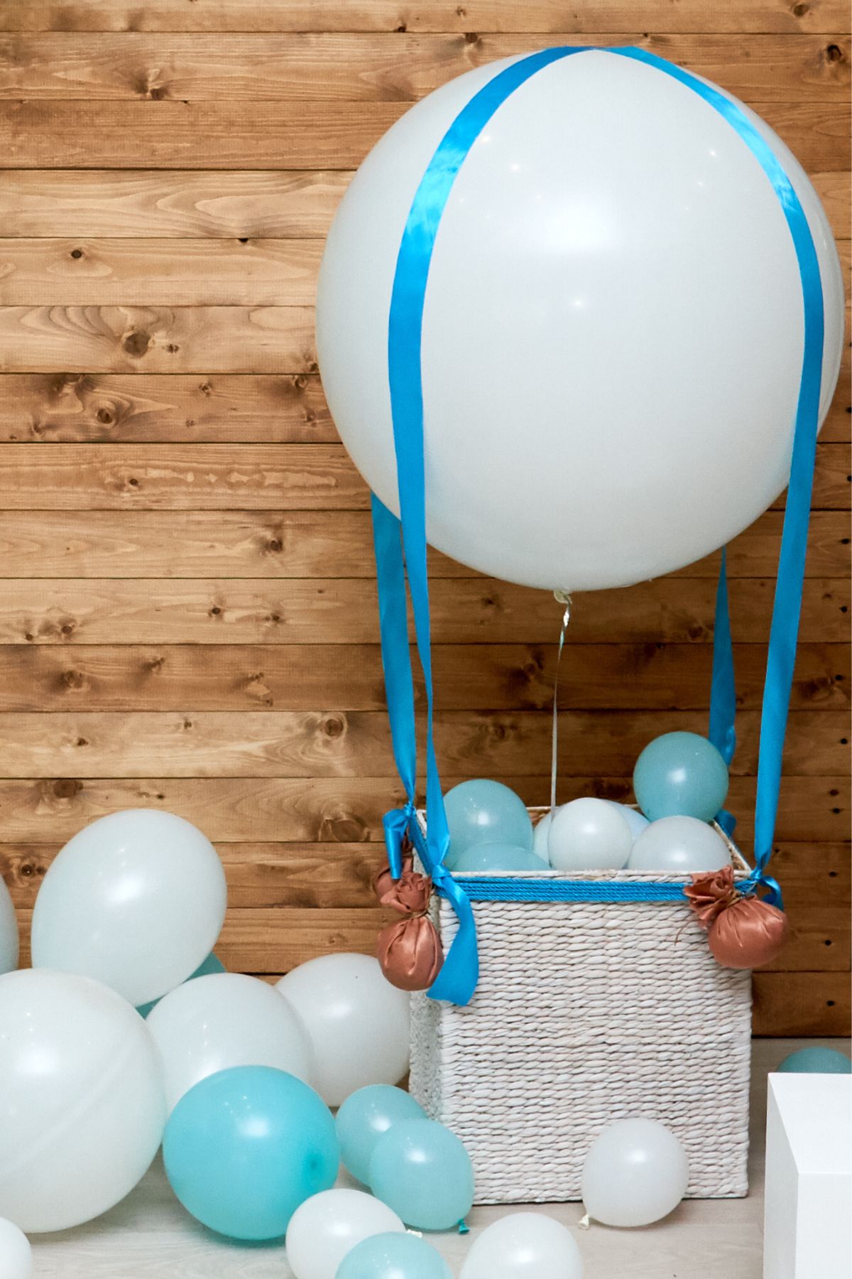 A mini hot air balloon baby shower decoration made from a wicker basket and ribbon.