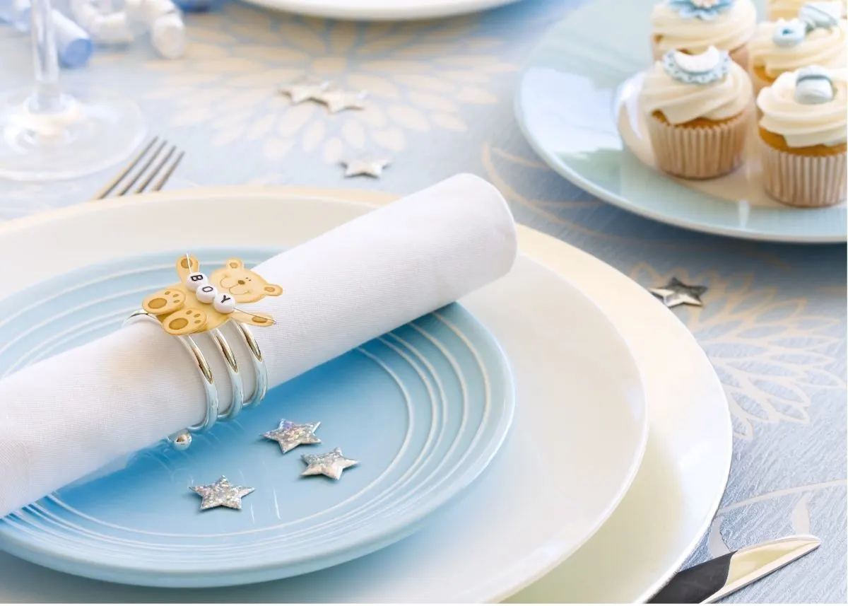 Blue and white place settings with a baby bear napkin ring on a table.