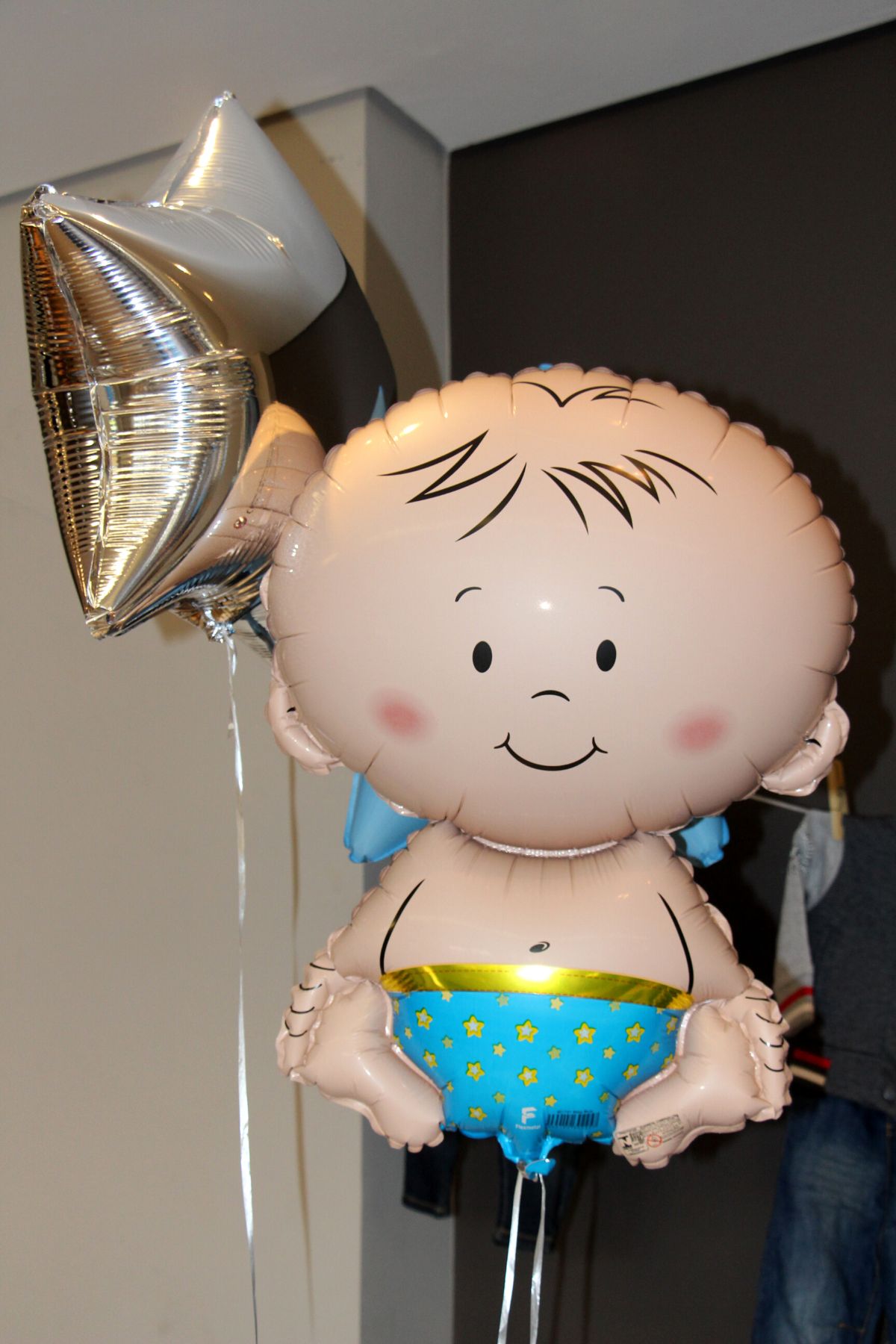 A foil helium baby balloon with a white ribbon.