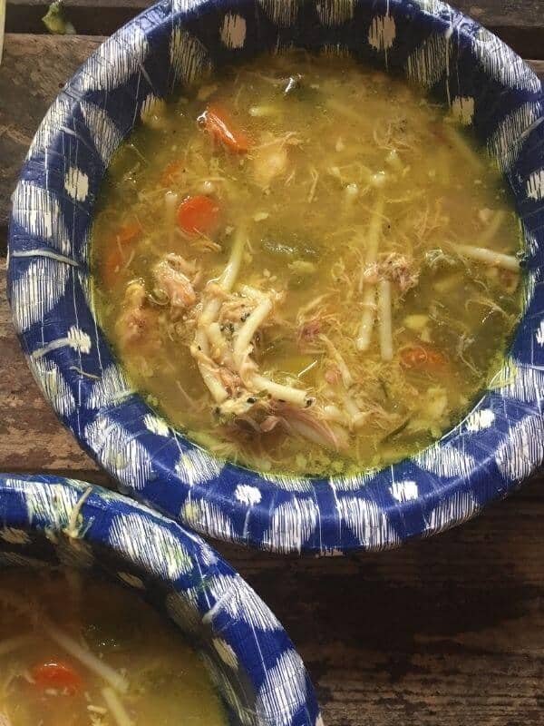 Lactation chicken noodle soup in to blue and white paper bowls.