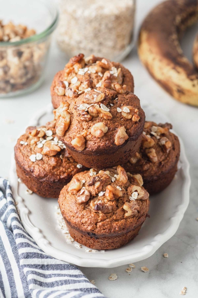 Banana oat lactation muffins piled on a white plate.