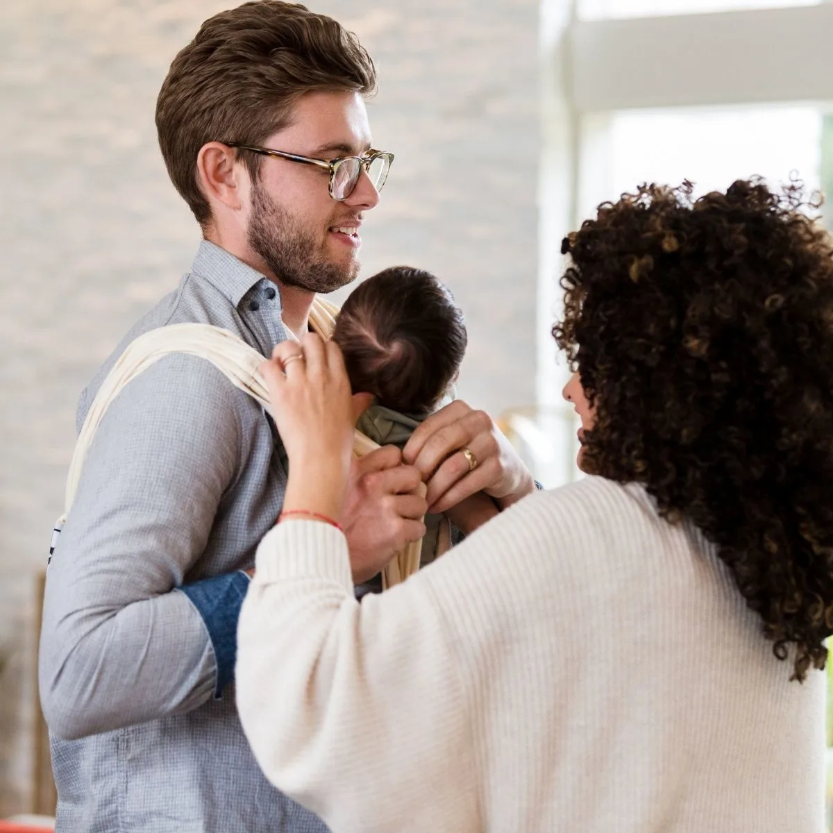 Mom helping dad wear a baby carrier safely