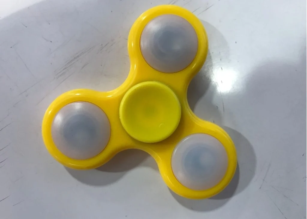 A yellow fidget spinner on a white background.