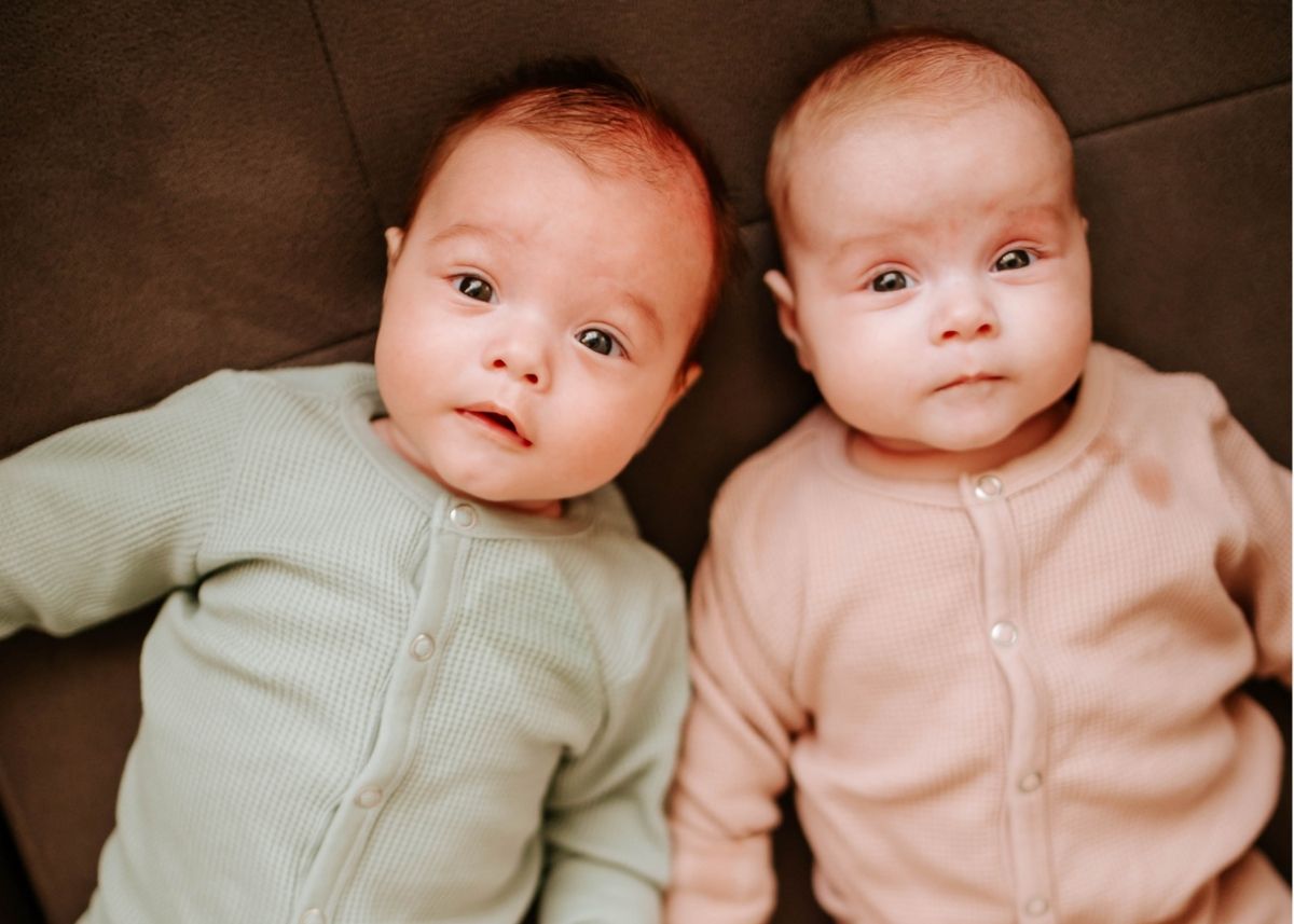 Boy and girl twins in a green and pink onesie.