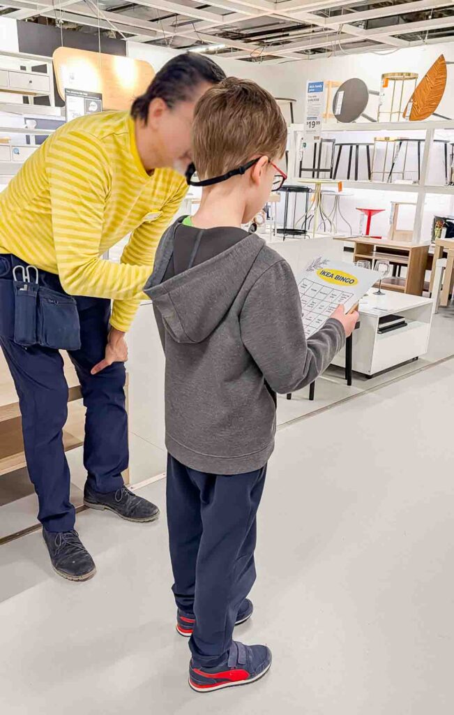 ikea-bingo-family-activity-2 Boy holding IKEA bingo with an employee helping him
